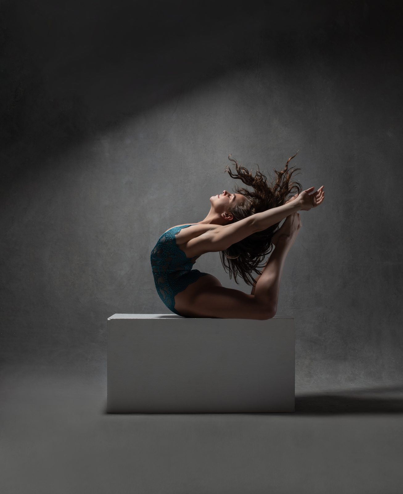 Full backbend arch on a pedestal, hair mid-flip