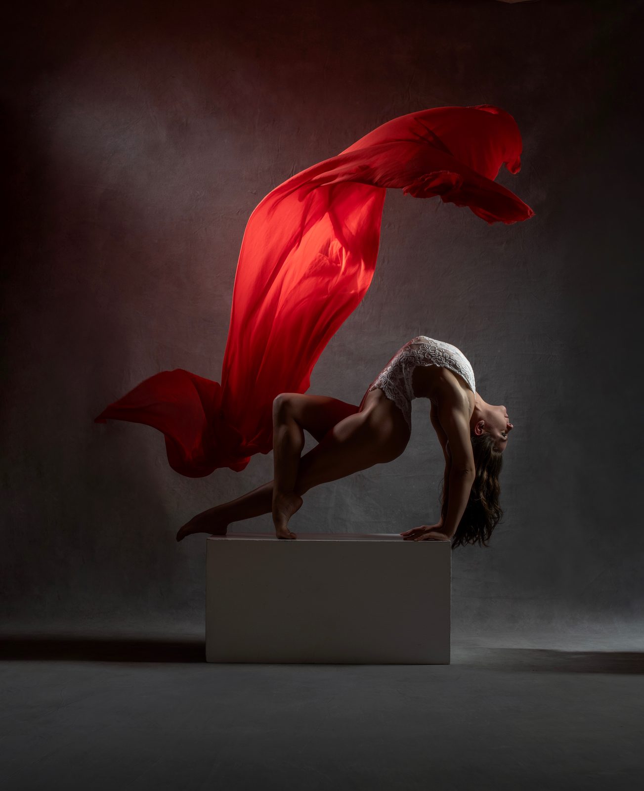 Contortion pose with sweeping red silk fabric