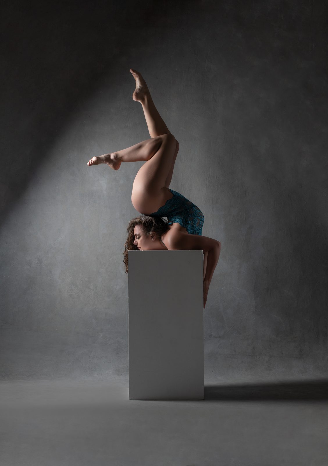 Elbow-stand contortion pose under a spotlight