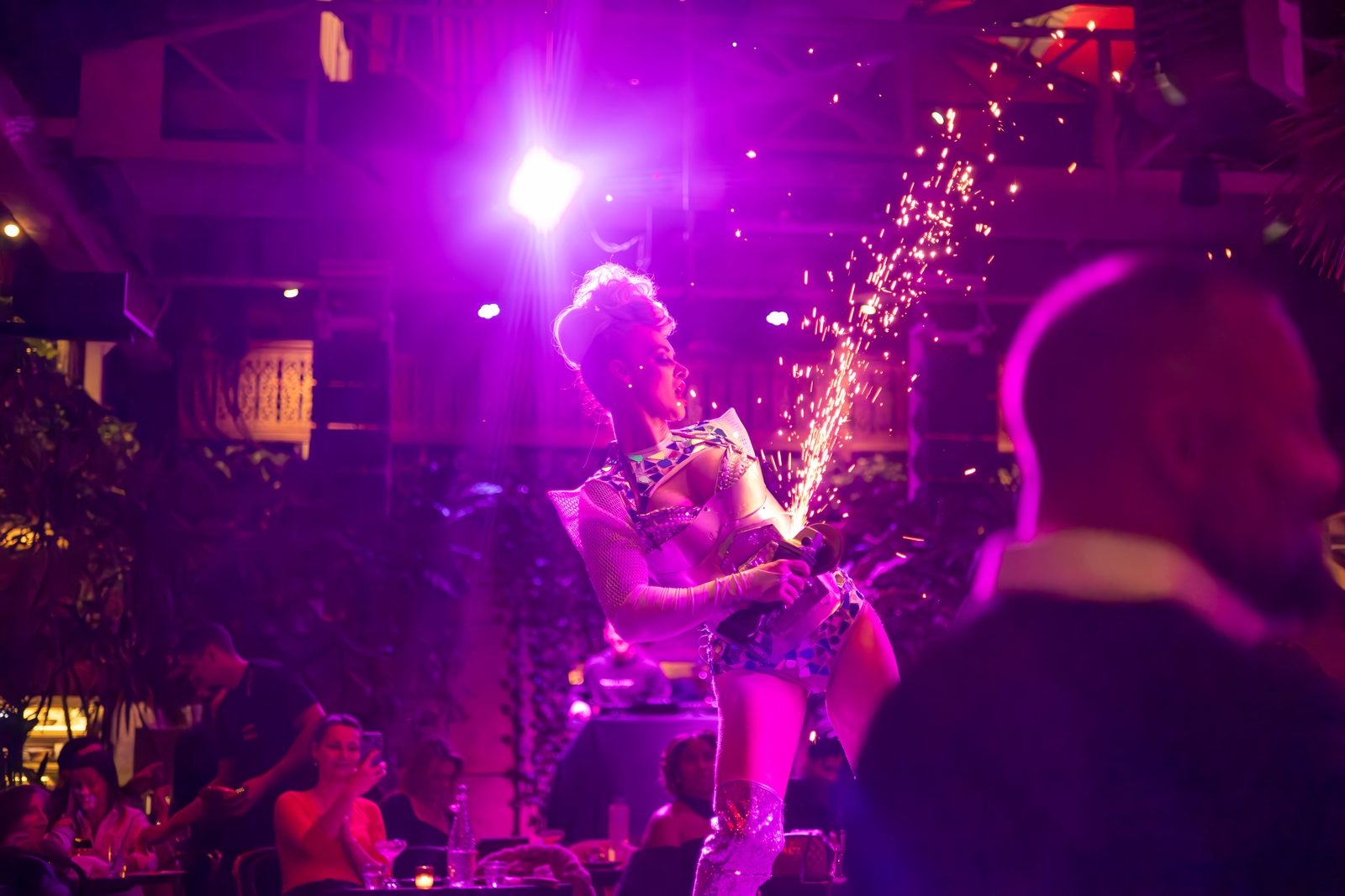 Grinder performer in a feathered headdress mid-spark-shower