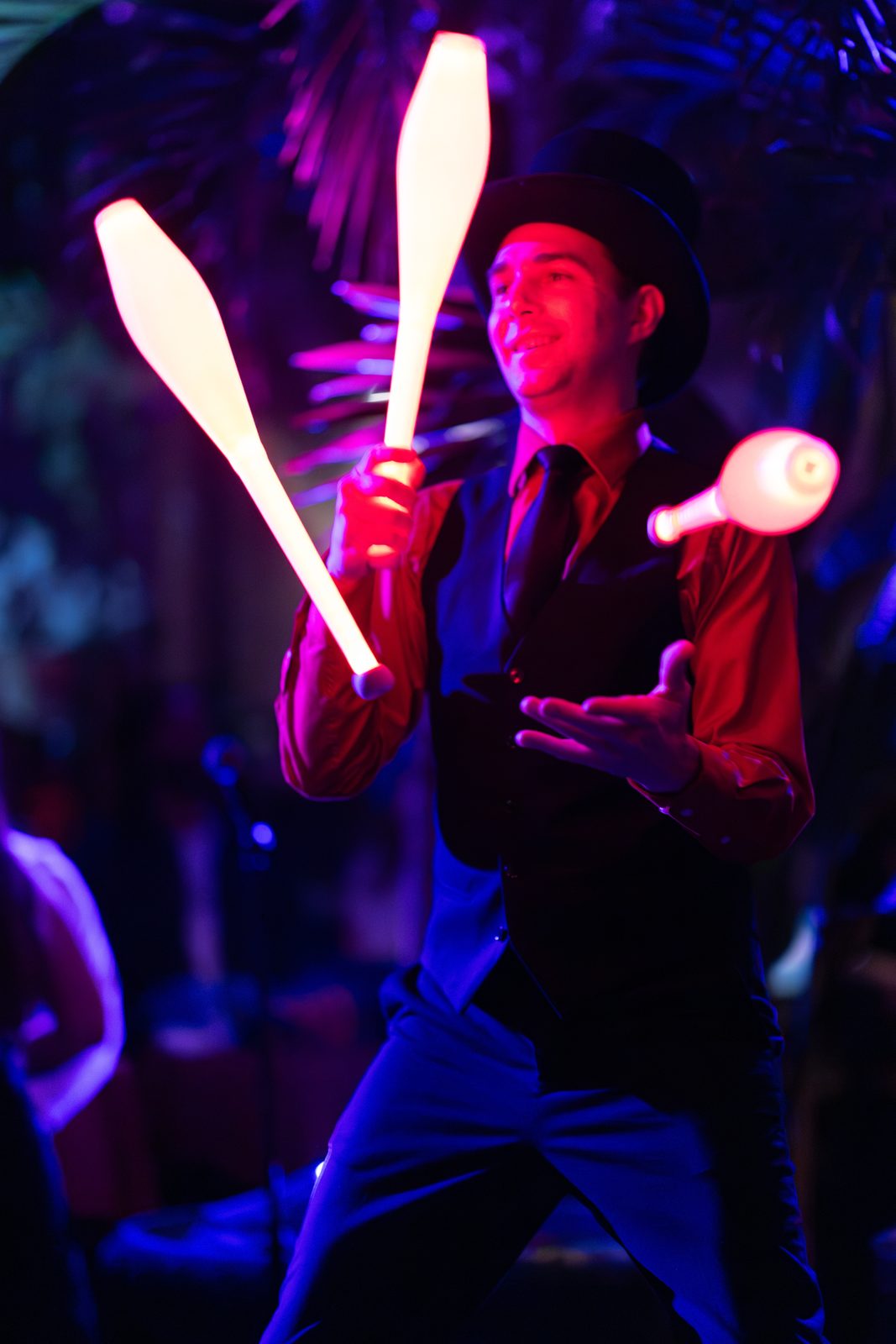 Juggler in a top hat tossing illuminated clubs