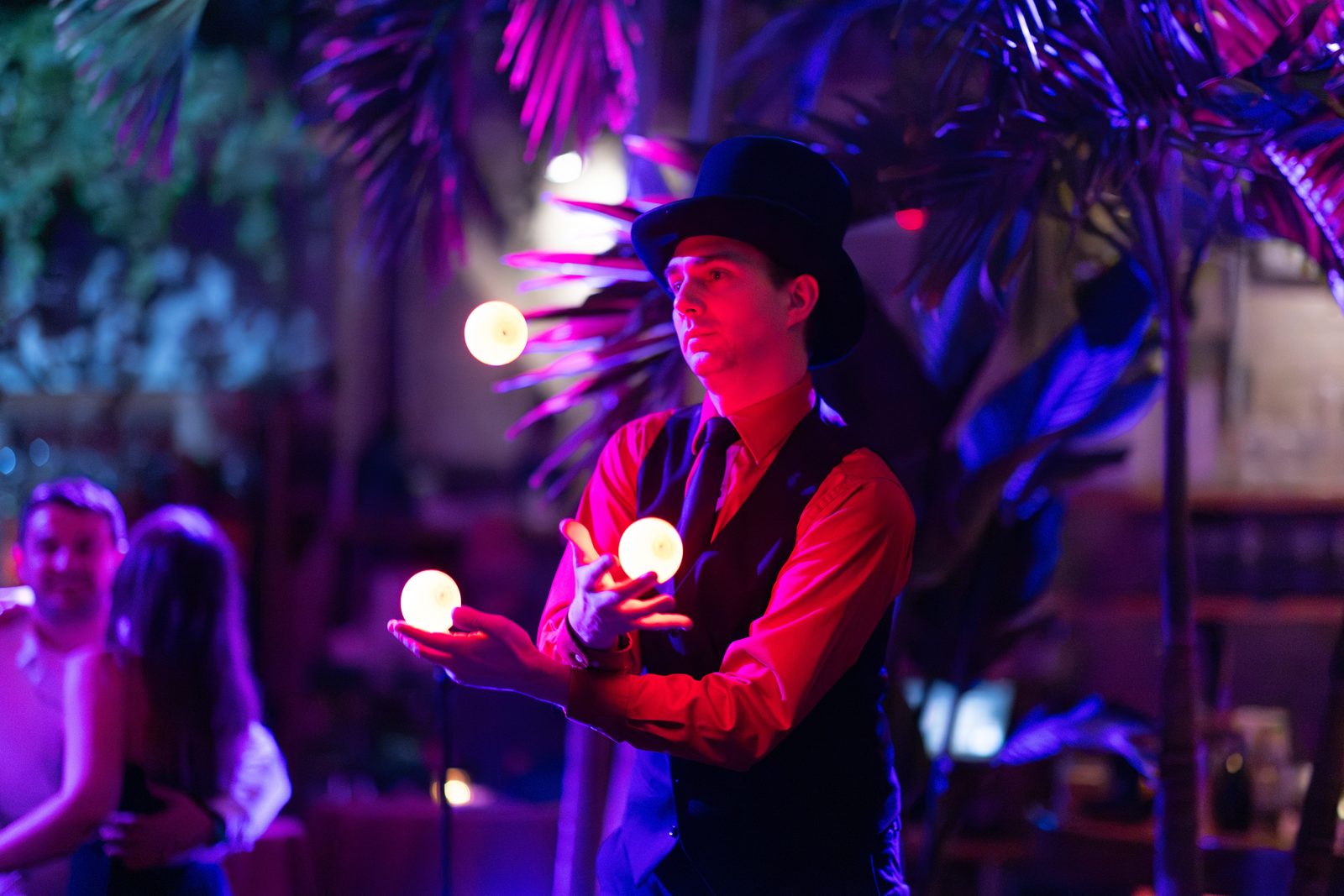 Top-hatted juggler tossing illuminated balls