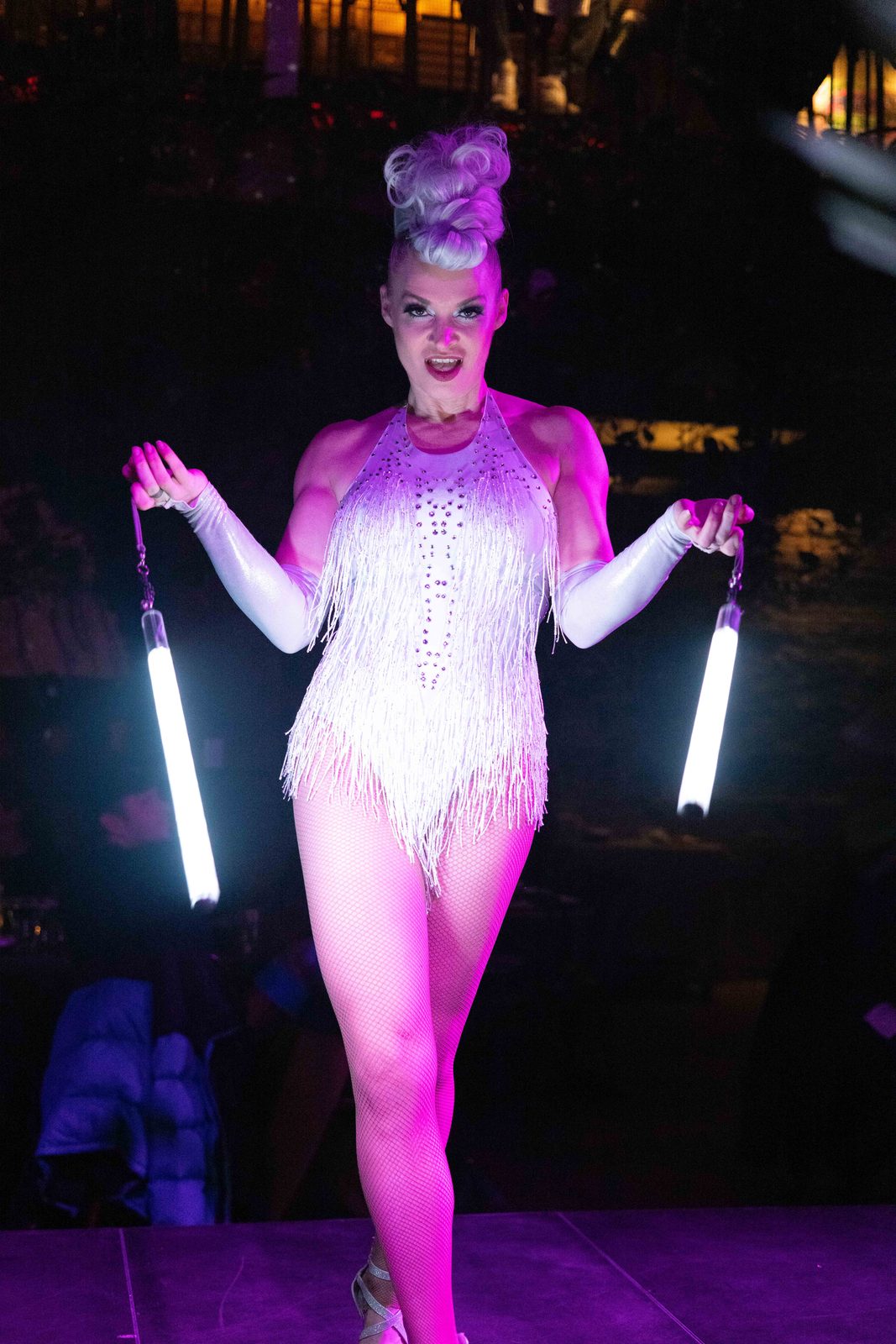 Glow performer in a sequined costume with LED batons