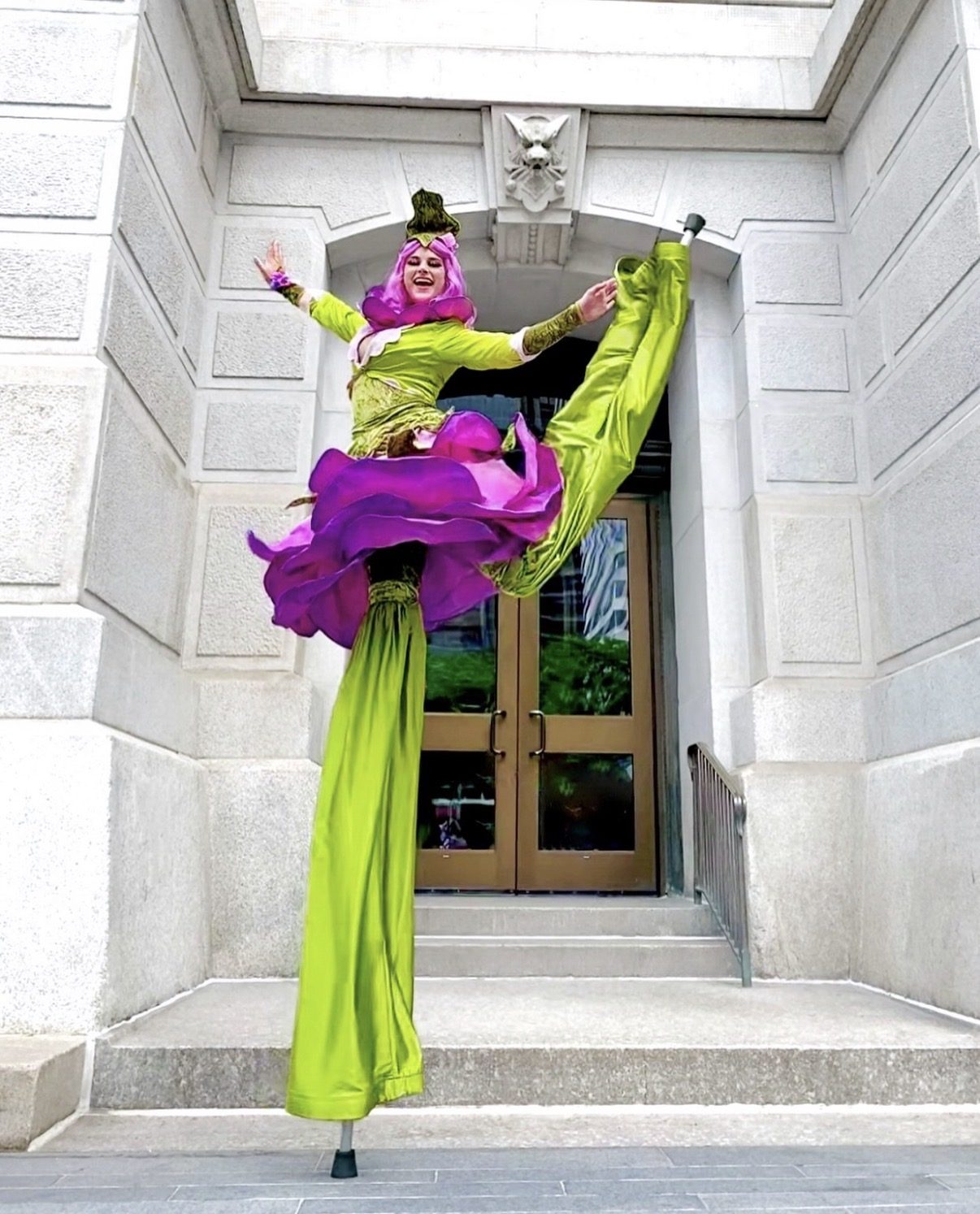 Stilt walker in a flowing green and purple costume outdoors