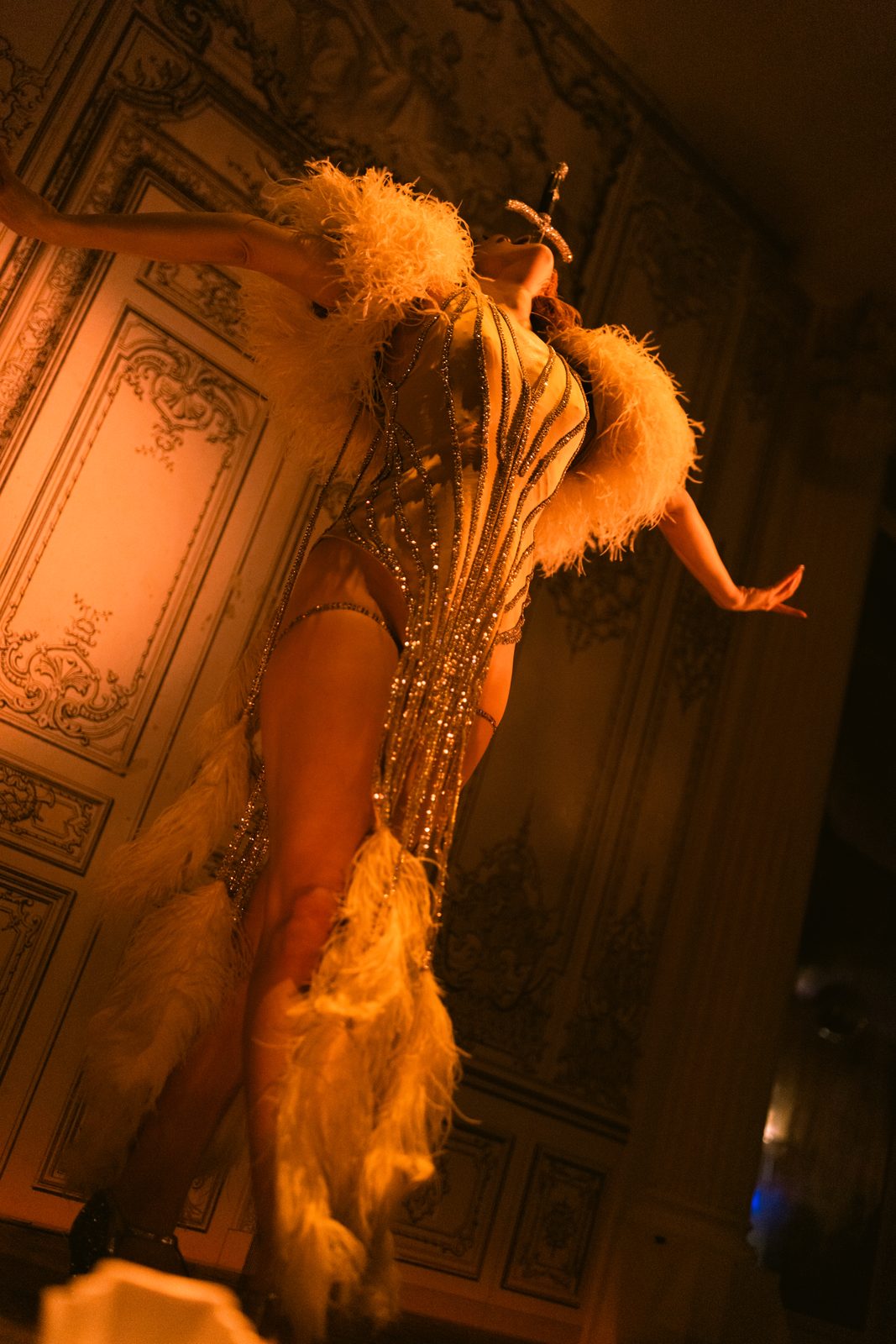 Sword swallower in golden light tilting back mid-swallow
