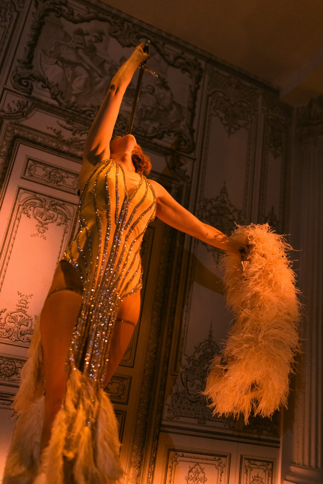 Sword swallower in a feathered costume mid-performance